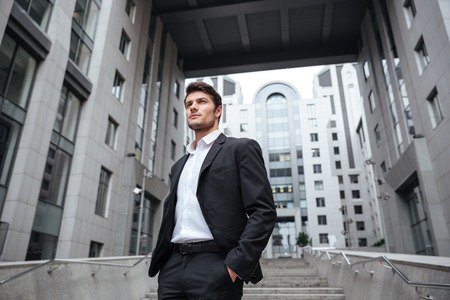 Portrait of handsome young businessman in suit standing near business centerの写真素材