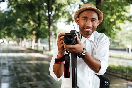 Funny black man in park with camera and hatの写真素材
