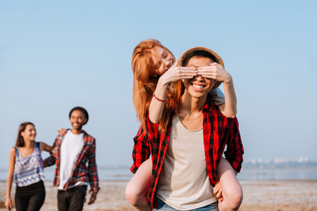 Happy redhead young woman covered eyes of her boyfriend by hands outdoorsの写真素材