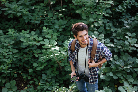 Top view of man in forest. smiling man with binoculars , map on phone and backpackの写真素材