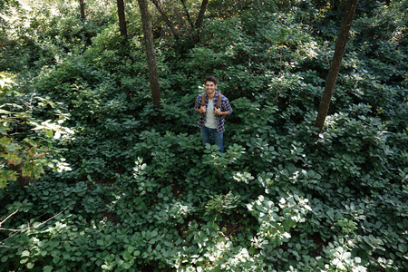 Full length image of young man in forest. from above. smiling man. holding hands on the harnessの写真素材