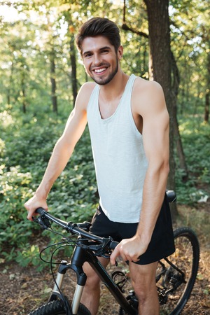 Vertical image of cyclist in forest. man looking at cameraの写真素材