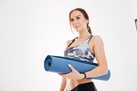 Fitness woman with mat. looking away. isolated white background