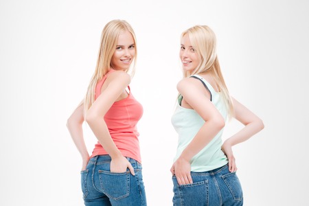 Picture of women dressed in t-shirts and jeans posing. Isolated over white background. Looking at the camera.の写真素材