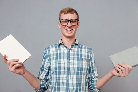 Student in glasses with books in studio. looking at camera. isolated gray backgroundの写真素材