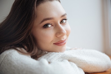 Close up model in sweater near the window. looking at camera.の写真素材