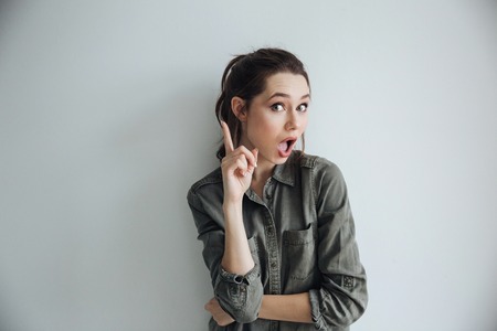 Woman in shirt showing up. looking at camera. isolated gray backgroundの写真素材