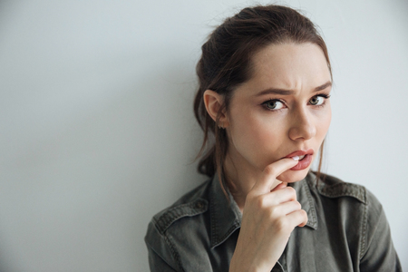 Thoughtful woman in shirt. hand near the face. looking at camera. isolated gray backgroundの写真素材