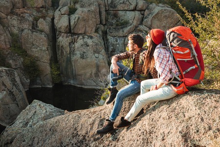 Adventure couple sitting on a rock. side view. couple looking awayの写真素材