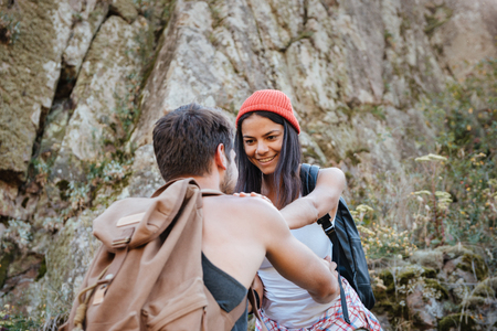 Young man and woman with backpacks walking on rockの写真素材