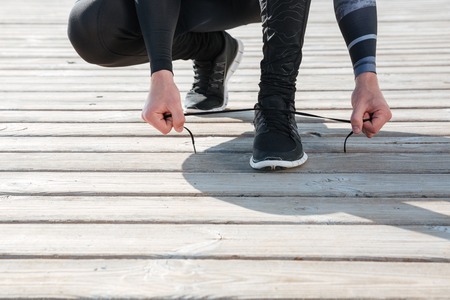 Cropped image of runner preparing near the sea. tying shoelacesの写真素材