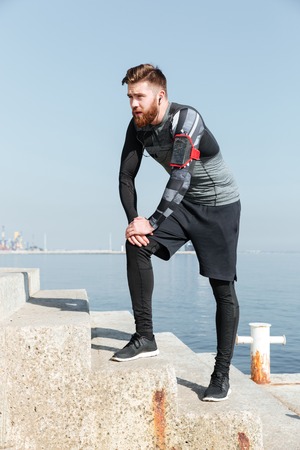 Tired runner on stairs near the sea. looking away. side view