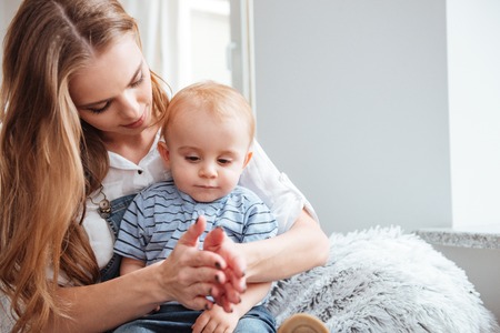 Beautiful young mother sitting and playing with her little son at homeの写真素材