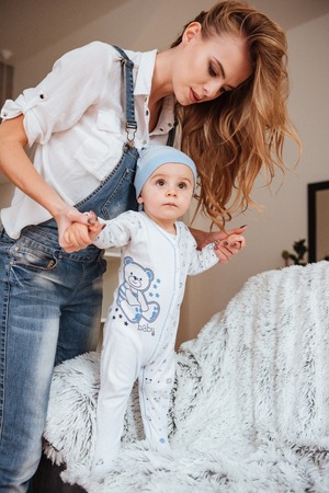 Beautiful young mother standing and taking care of her little son at home