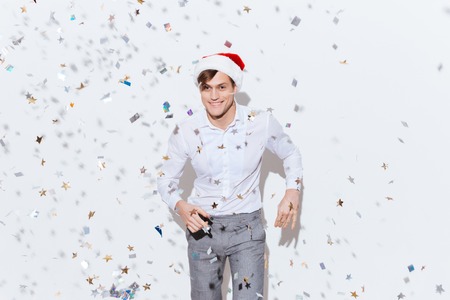 Happy handsome young businessman in santa claus hat dancing and smiling over white background
