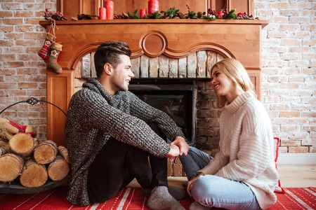 Couple in sweaters sitting on the floor near the fireplace. eyes to eyesの写真素材