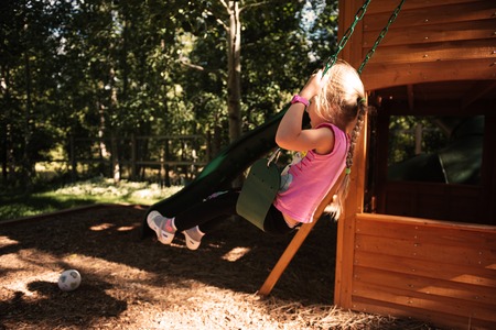 Girl on playground. side view. rides on a swingの写真素材