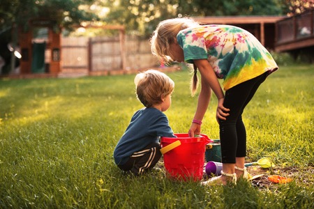 Young boy and girl on playground. back view. on grassの写真素材