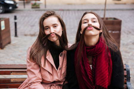 Funny friends in coats on the benchの写真素材