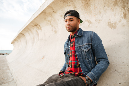 Image of african man wearing cap walking on the beach. Looking at camera.の写真素材