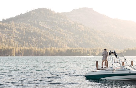 Man standing on a boat and watching at beautiful mountains and lake landscapeの写真素材