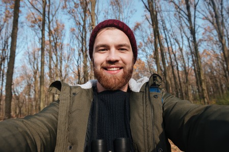 Image of young bearded man making selfie in the forest. Looking at camera and smile.の写真素材