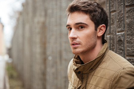 Picture of attractive young man walking on the street and looking aside.