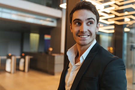 Close up smiling bisiness man in suit looking away in office