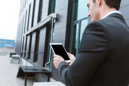 Back view of Business man in shirt using laptop near the officeの写真素材