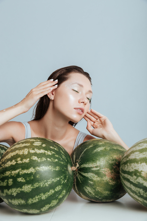 Beauty portrait of attractive young woman with eyes closed and fresh watermelonsの写真素材