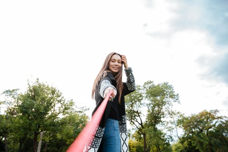 Cheerful attractive young woman walking with dog in park