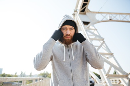 Portrait of a young sport athlete man in hoodie standing at the urban bridgeの写真素材