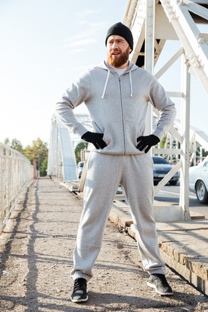 Full length portrait of a young bearded sports man taking break after workout outdoorsの写真素材