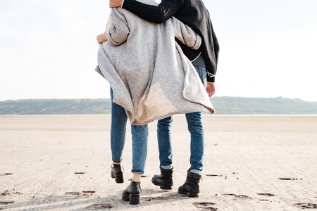 Cropped image of a young couple in casual clothes walking along seashoreの写真素材