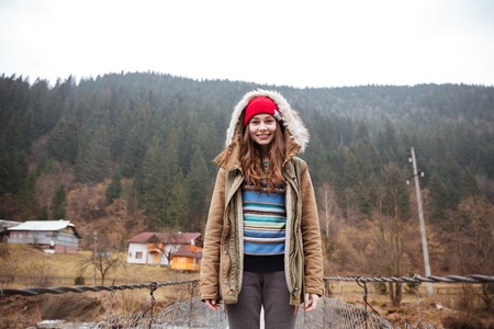 Picture of young pretty lady standing in the mountains and looking at camera.