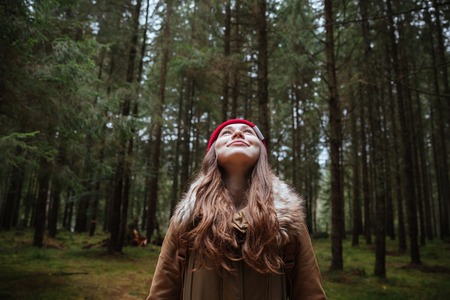 Photo of happy young lady standing in the forest. Looking aside.の写真素材