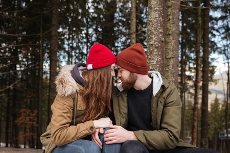 Image of young happy loving couple sitting over forest and hugging. Look at each other.の写真素材
