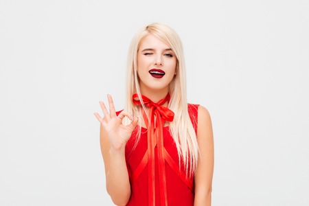 Flirting woman shows ok. model in red dress. so prettyの写真素材