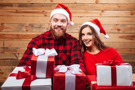 Happy friends with gifts. in chrismas hats. looking at cameraの写真素材