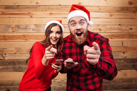 Pretty friends in santa's hats with phone. shows at cameraの写真素材