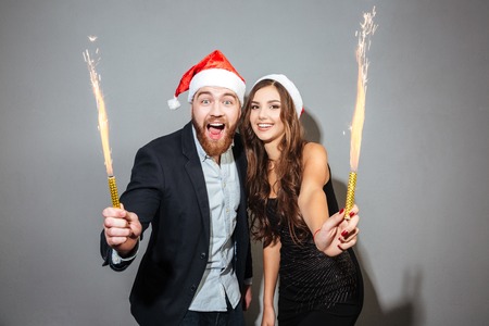 Christmas couple with sparklers. so happe. gray backgroundの写真素材