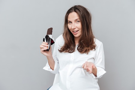 Happy pregnant woman with chocolate. looking at camera.の写真素材