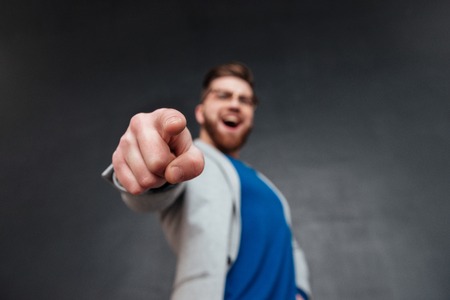 Man pointing his fingers on camera. laughing. in studio. isolated black backgroundの写真素材