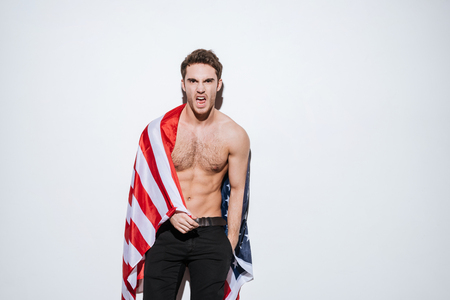 Photo of attractive businessman posing at studio and look at camera while holding USA flag. Isolated over white background.の写真素材