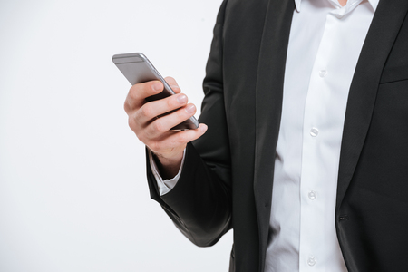 Cropped image of a man in suit holding mobile phone over white backgroundの写真素材