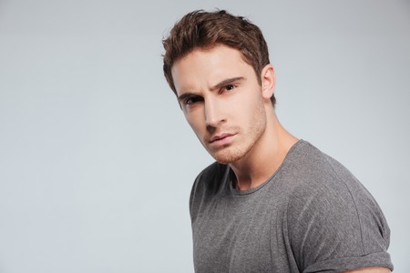 Close up portrait of a serious casual man staring at camera over white backgroundの写真素材