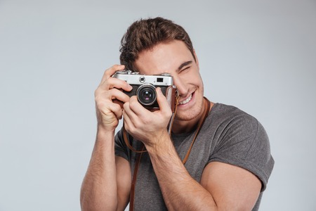 Portrait of a young man photographer with camera taking photo isolated on a white backgroundの写真素材