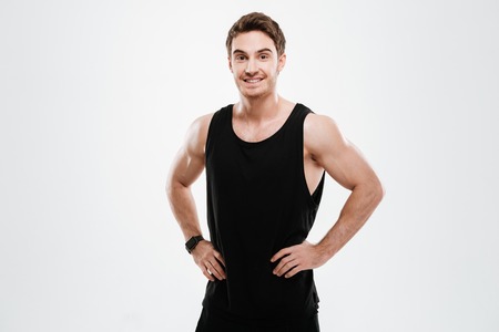Photo of attractive cheerful young man dressed in black t-shirt standing over white background and looking to camera.の写真素材