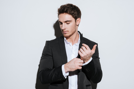 Image of handsome serious businessman standing at studio and look aside. Isolated over white background.の写真素材