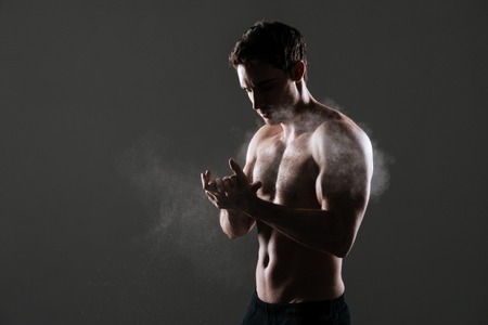 Picture of handsome sportsman standing in gym over grey background before training.の写真素材